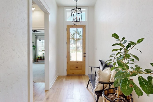 doorway to outside with an inviting chandelier and light wood-type flooring