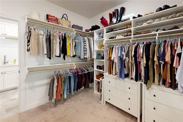 spacious closet featuring light colored carpet and a sink
