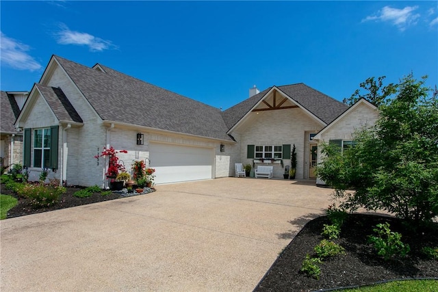view of front of house with a chimney, brick siding, a garage, a shingled roof, and concrete driveway