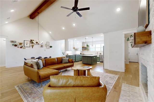 living area featuring ceiling fan with notable chandelier, beam ceiling, high vaulted ceiling, ornate columns, and light wood-style flooring