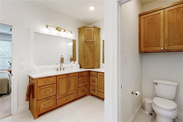 ensuite bathroom with toilet, marble finish floor, baseboards, ensuite bath, and vanity
