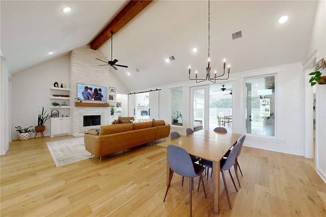 dining room with ceiling fan with notable chandelier, beam ceiling, high vaulted ceiling, visible vents, and a large fireplace