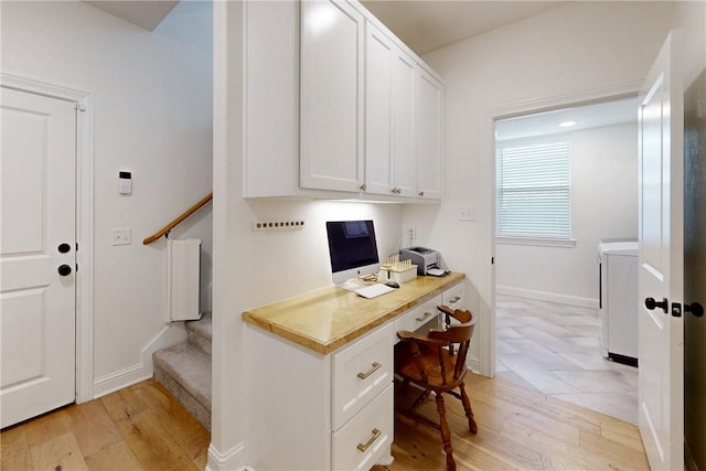 office space with radiator heating unit, washer / dryer, light wood-type flooring, and built in desk
