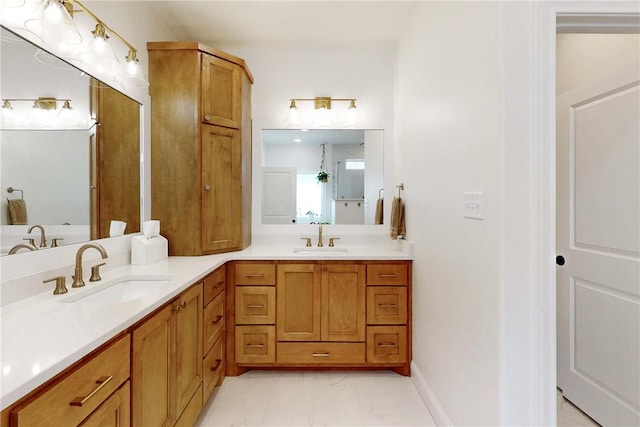 bathroom featuring baseboards, marble finish floor, double vanity, and a sink