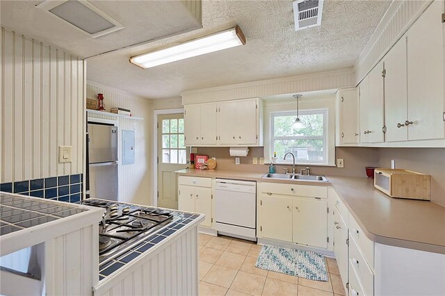 809 Coulter Dr S, Bryan, TX 77803 - kitchen featuring white dishwasher, sink, light tile patterned floors, white cabinetry, and stainless steel refrigerator