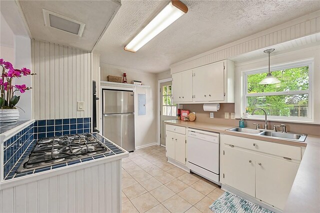 809 Coulter Dr S, Bryan, TX 77803 - kitchen featuring dishwasher, white cabinets, sink, hanging light fixtures, and stainless steel refrigerator