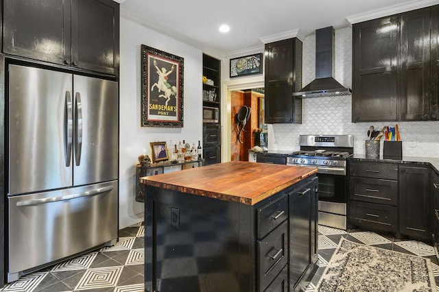 kitchen featuring appliances with stainless steel finishes, tasteful backsplash, ornamental molding, wall chimney exhaust hood, and a kitchen island