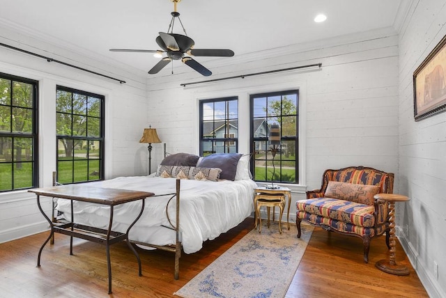 bedroom with multiple windows, ceiling fan, hardwood / wood-style floors, and ornamental molding