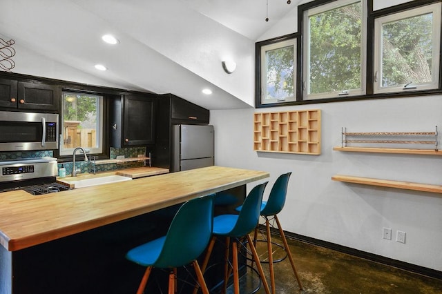 kitchen featuring a breakfast bar, wood counters, lofted ceiling, and stainless steel appliances