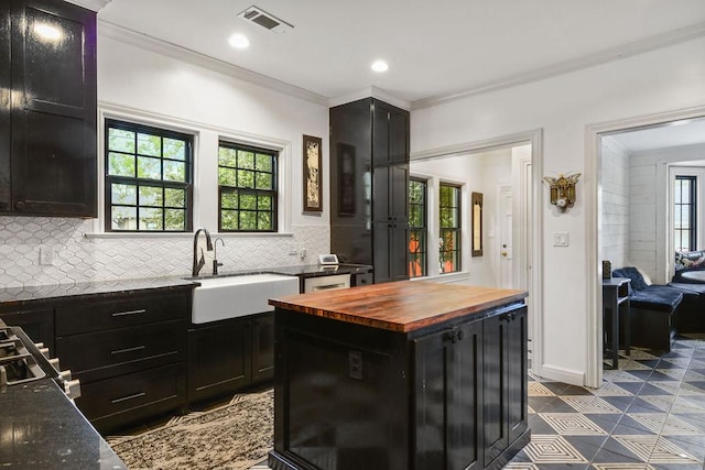 kitchen with butcher block countertops, a kitchen island, tasteful backsplash, and sink