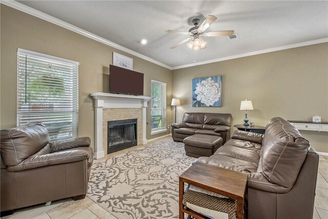 living area with a tiled fireplace, a healthy amount of sunlight, and ornamental molding