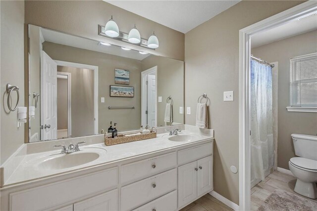 full bathroom with a sink, baseboards, toilet, and double vanity