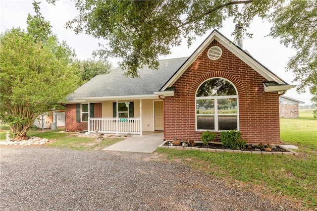 9939 County Road 272, Somerville, TX 77879 - ranch-style home featuring a porch, brick siding, a front yard, and a shingled roof