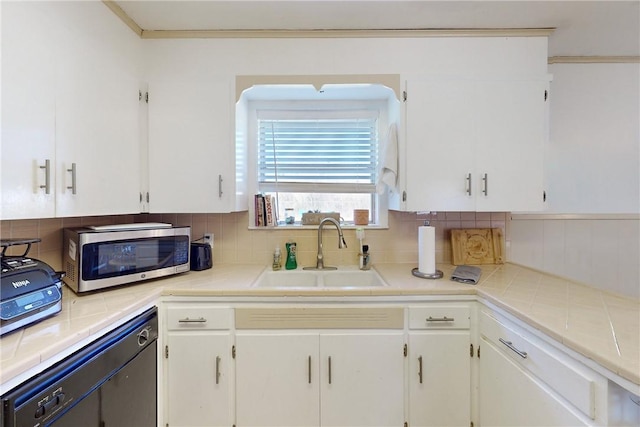 kitchen featuring sink, white cabinets, tasteful backsplash, and black dishwasher