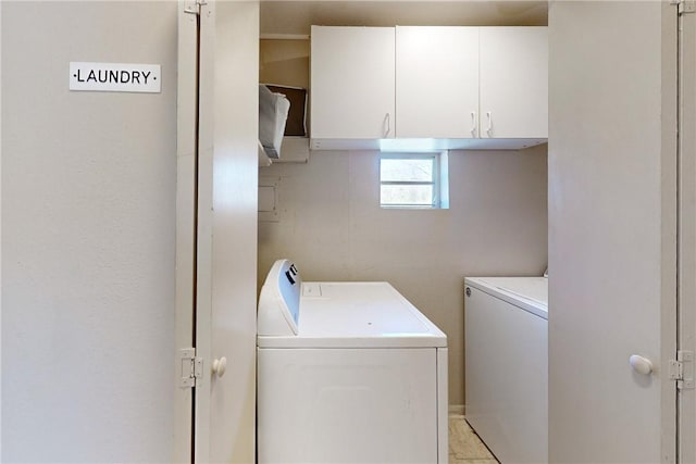 clothes washing area with washer and clothes dryer and cabinets