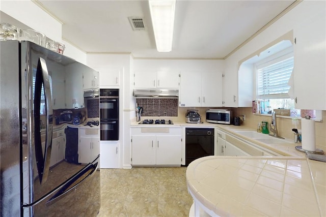 kitchen with black appliances, tasteful backsplash, crown molding, white cabinets, and sink