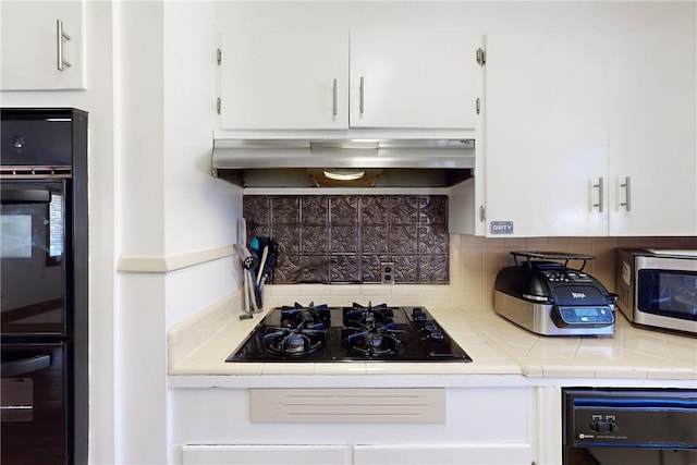 kitchen featuring black gas stovetop, extractor fan, white cabinetry, and decorative backsplash