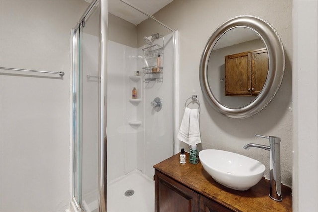 bathroom featuring a shower with shower door and vanity