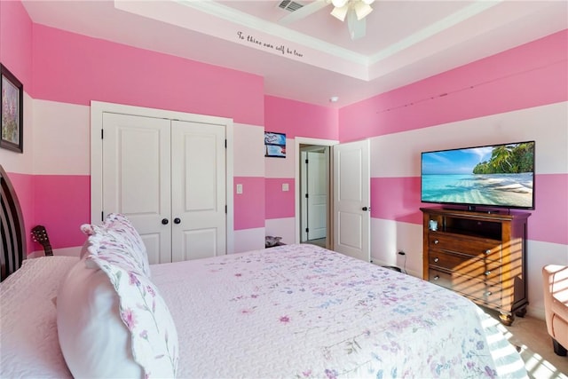 bedroom with carpet, ceiling fan, a tray ceiling, and a closet