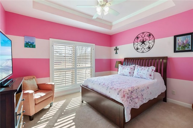 bedroom with baseboards, ceiling fan, ornamental molding, carpet, and a tray ceiling