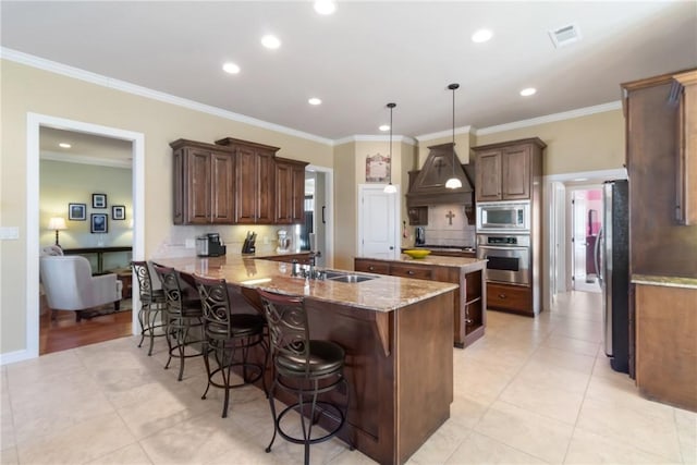 kitchen featuring crown molding, stainless steel appliances, a sink, and a kitchen breakfast bar