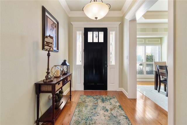 foyer with wood finished floors and crown molding