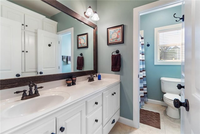 bathroom with baseboards, a sink, toilet, and double vanity