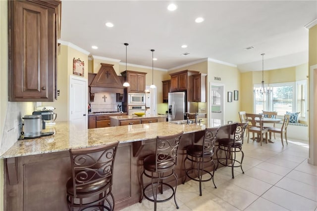 kitchen with tasteful backsplash, appliances with stainless steel finishes, a sink, light stone countertops, and a peninsula