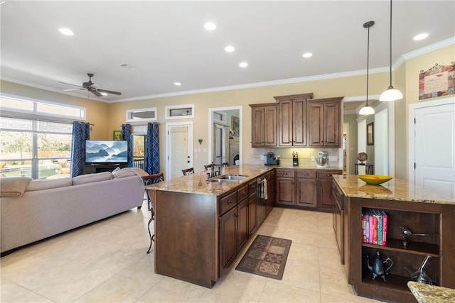 kitchen featuring ornamental molding, open floor plan, a sink, light stone countertops, and a kitchen bar