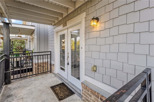 property entrance featuring covered porch and french doors