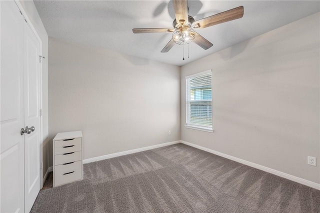 unfurnished bedroom featuring ceiling fan, dark carpet, and a closet