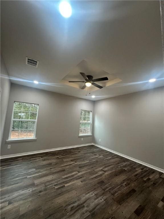 unfurnished room with a raised ceiling, ceiling fan, and dark hardwood / wood-style flooring