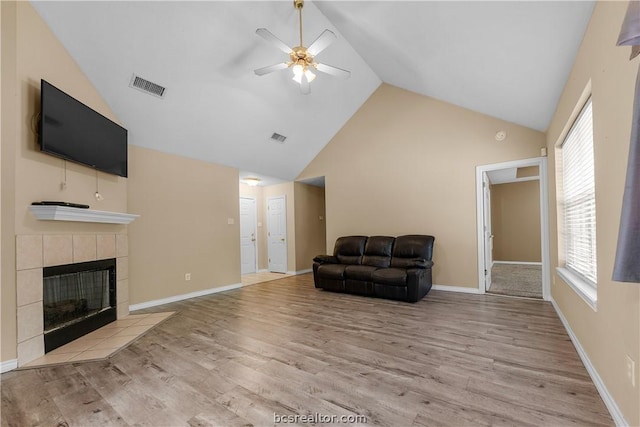 sitting room with a tile fireplace, high vaulted ceiling, light hardwood / wood-style flooring, and ceiling fan