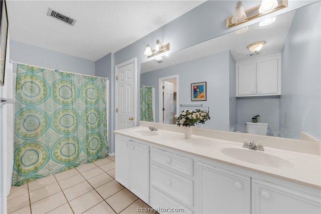 bathroom with toilet, vanity, and tile patterned floors