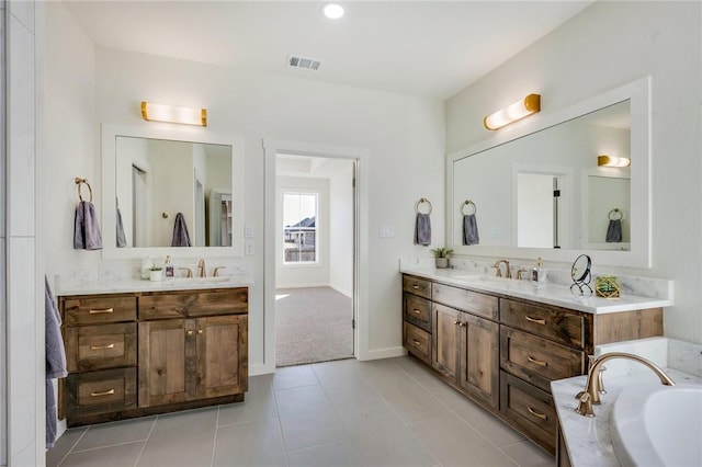 bathroom featuring baseboards, visible vents, a tub, tile patterned floors, and two vanities