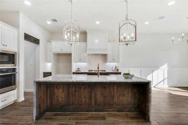 kitchen with dark wood-style floors, stainless steel appliances, visible vents, and a notable chandelier