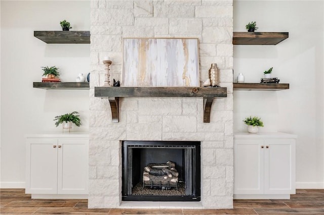 interior details with wood tiled floor, a stone fireplace, and baseboards