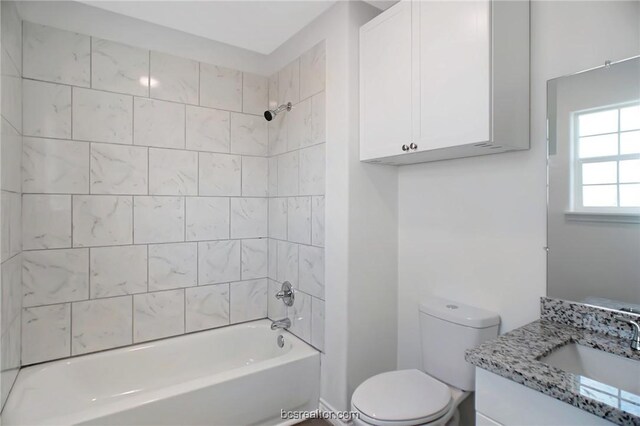 full bathroom featuring vanity, tiled shower / bath combo, and toilet