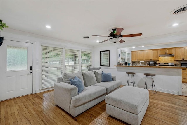 living room with plenty of natural light, ceiling fan, crown molding, and light hardwood / wood-style flooring