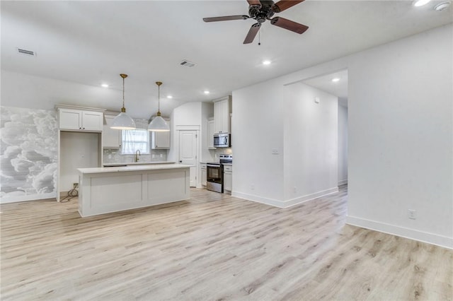 kitchen featuring light wood finished floors, visible vents, light countertops, decorative backsplash, and appliances with stainless steel finishes