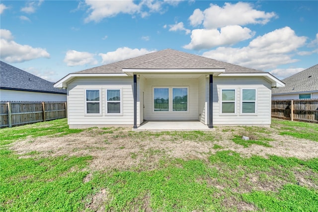 back of property featuring a patio, a yard, a fenced backyard, and roof with shingles