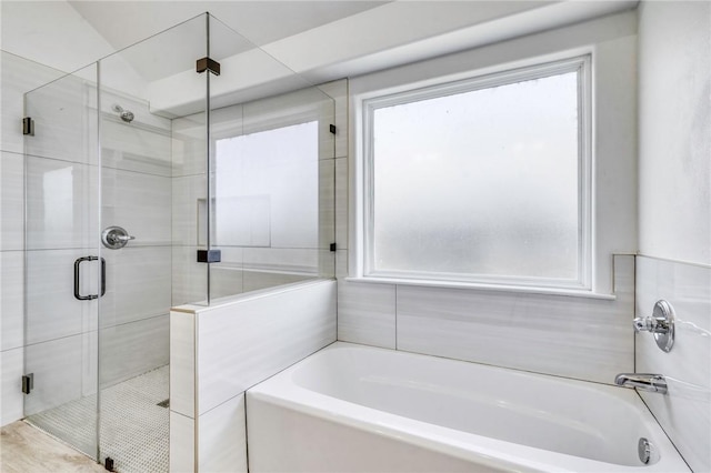 full bathroom featuring a wealth of natural light, a stall shower, and a garden tub