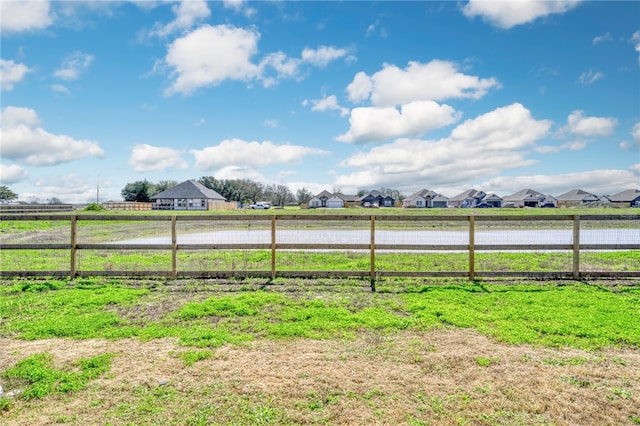 view of yard featuring a rural view, fence, and a residential view