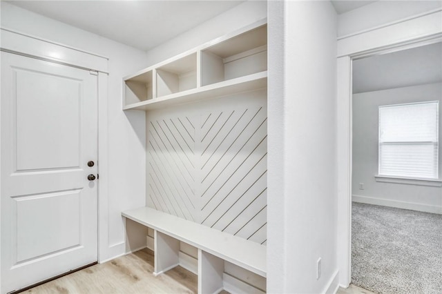 mudroom featuring light colored carpet and baseboards