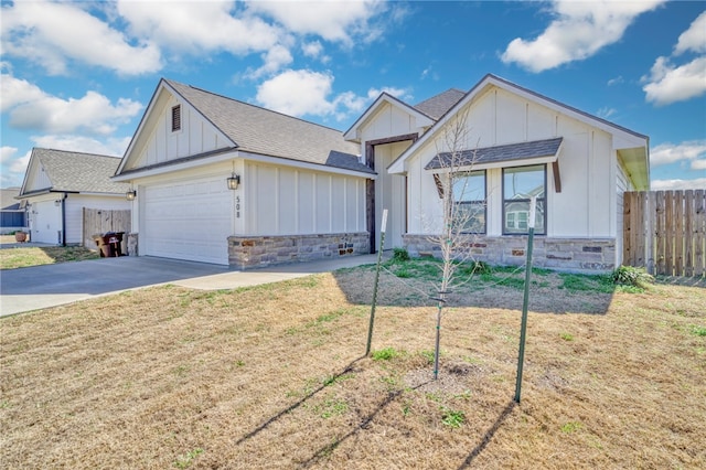 modern farmhouse with stone siding, board and batten siding, concrete driveway, and fence