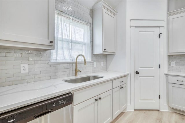 kitchen with dishwasher, light stone counters, light wood-style flooring, white cabinets, and a sink