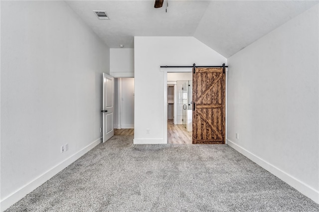 unfurnished bedroom with a barn door, baseboards, visible vents, and carpet flooring