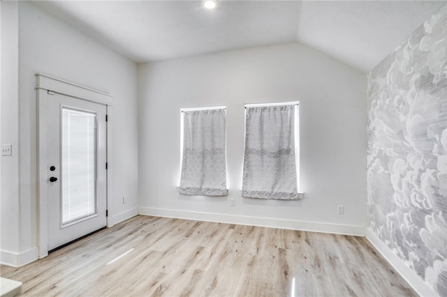 foyer featuring baseboards, lofted ceiling, and wood finished floors