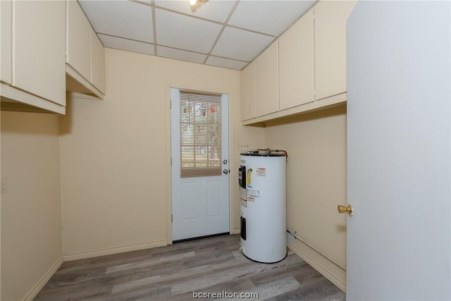 clothes washing area with water heater and light hardwood / wood-style flooring