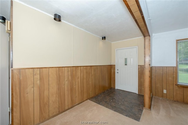 entrance foyer featuring light carpet, crown molding, and wooden walls